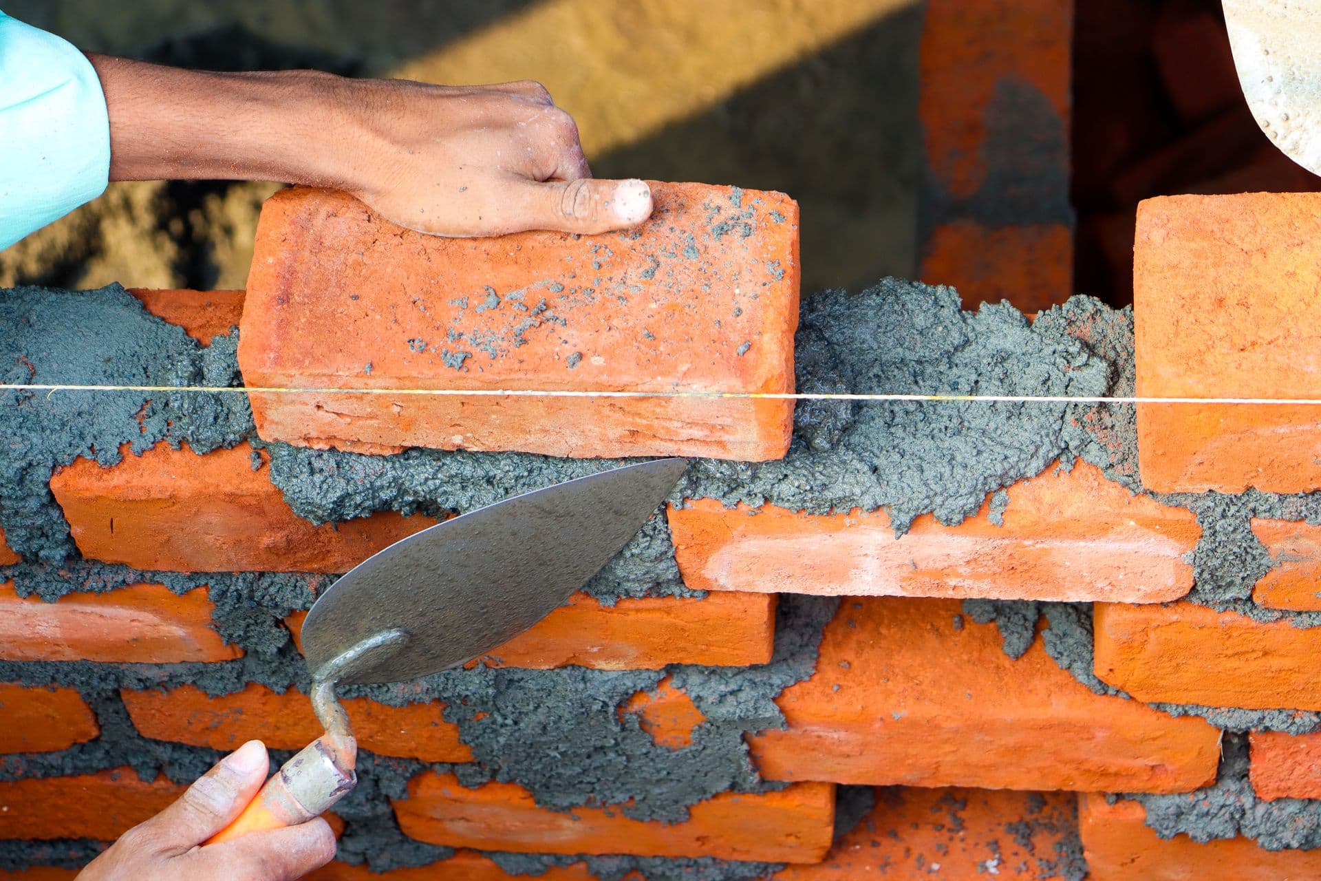 Mason laying brick with trowel and mortar