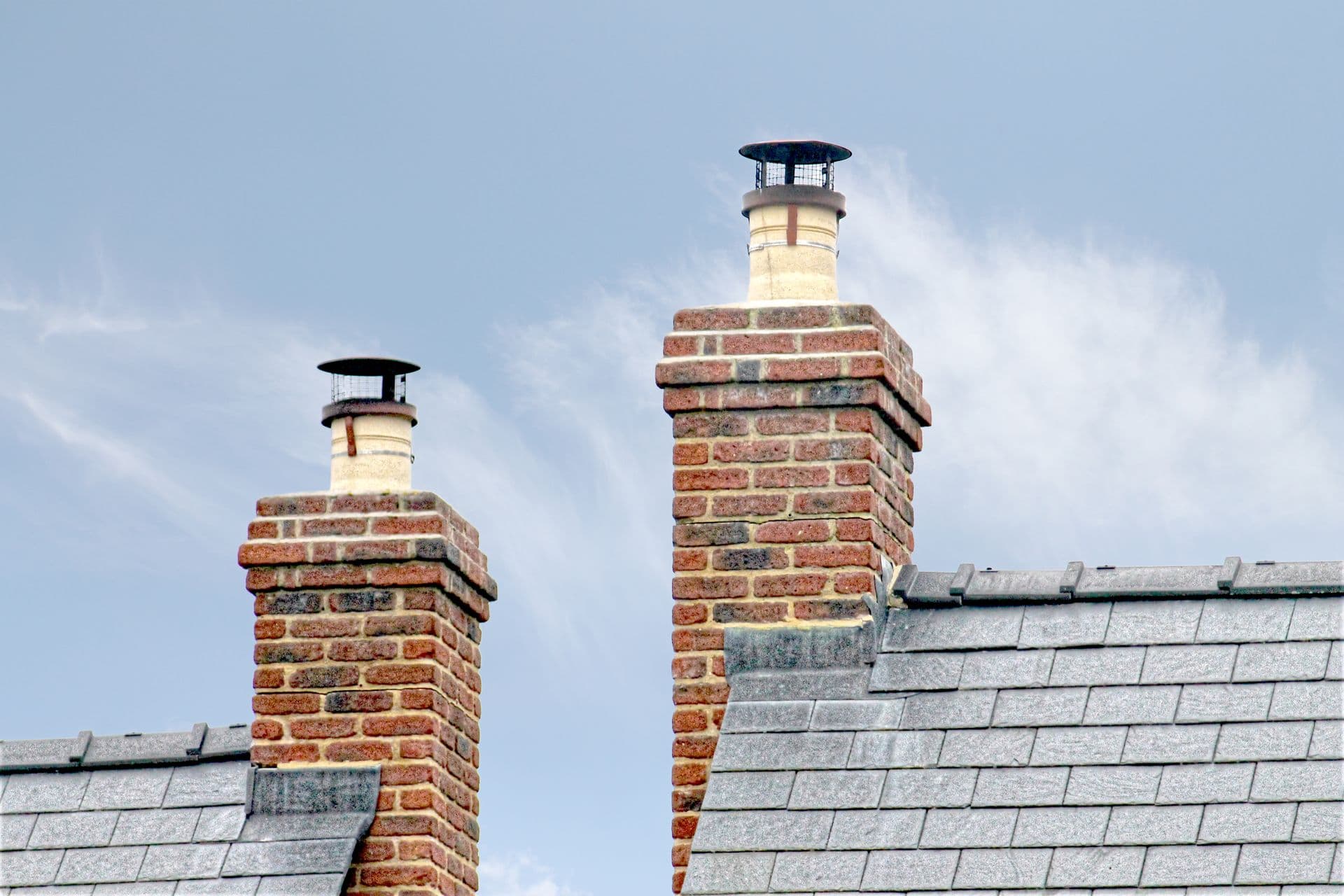 Brick chimneys with new caps on a residential roof